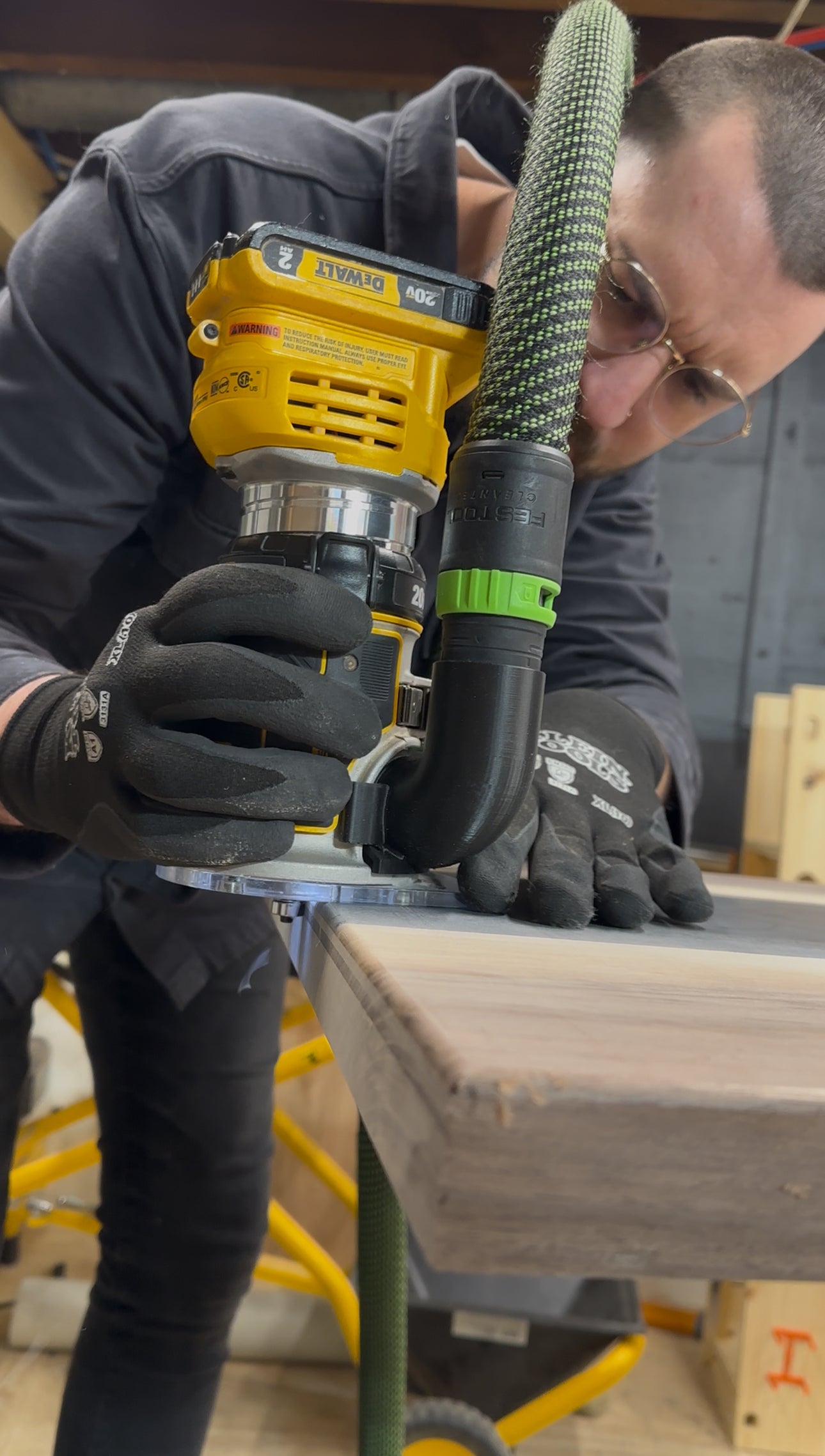 Person using a power tool with a hose attachment on a wooden surface